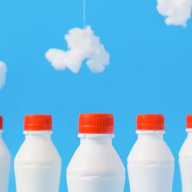 Milk bottles with red caps against a background with cloudy sky