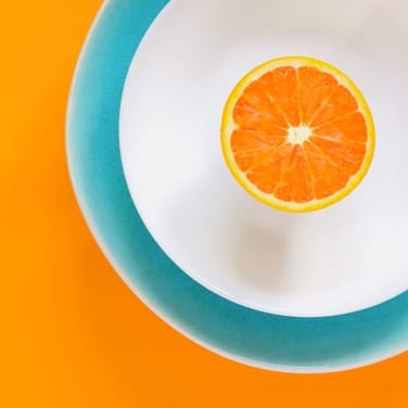 Half of an orange on two plates on an orange background