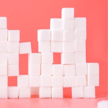 A structure built with sugar cubes on a pinkish red background