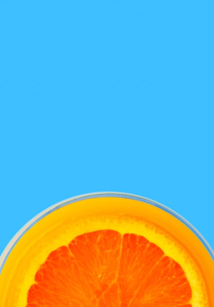 Half of an orange in a glass on a blue background