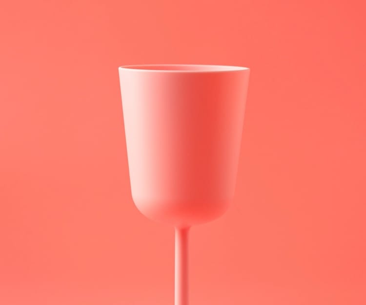 Drinking glass in a pinkish red colour on pinkish red background